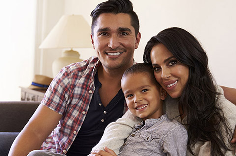 Portrait Of Happy Family Sitting On Sofa In at Home